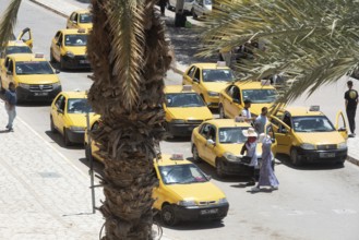 Streets of Sfax busy with taxi cabs waiting outside ancient fortified gate of Sfax Medina, known as