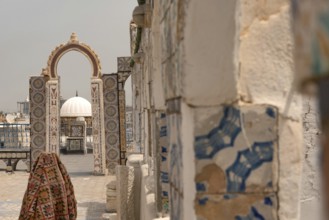 A rooftop view of a domed building through an archway decorated with traditional mosaic designs,