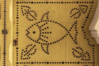 Distinctive fish design, an architectural detail of a traditional yellow painted door in the Medina