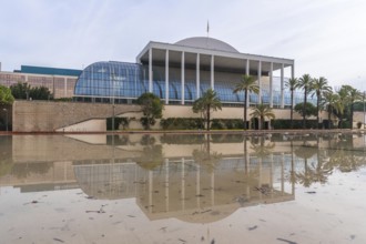 The palau de la musica music hall in valencia, spain, reflecting in a large permanent water feature