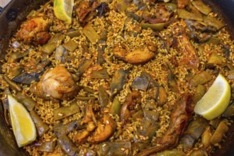 Authentic valencia paella cooking in a wide shallow pan, showcasing flavorful rice, seasoned