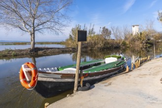 Traditional fishing boat with an orange lifebuoy tied to its bow, moored at a concrete dock beside