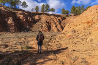 Woman with a backpack hiking through the dry, eroded landscape of las arcillas natural park in