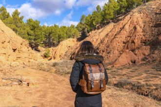 Woman with a backpack exploring the scenic red clay canyons and erosion features of las arcillas