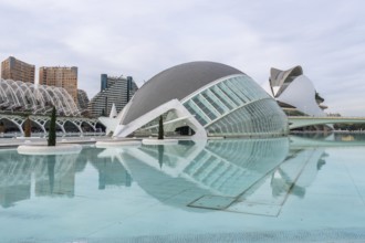 Hemisferic building reflecting in turquoise lagoon at the city of arts and sciences in valencia,