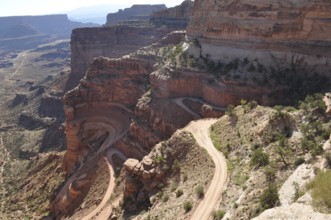 Narrow gravel road winds along steep rocks in a canyon landscape, Canyonlands National Park, Island