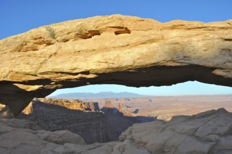 Well-known Mesa Arch rock arch in desert landscape with extensive views of canyon, Canyonlands