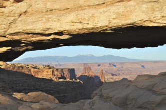Natural Mesa Arch rock arch with views of mountains and canyon landscape, Canyonlands National