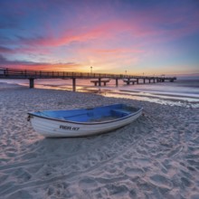 Pier on the fine sandy beach of the Baltic Sea at sunset, fishing boat on the beach, Baltic resort