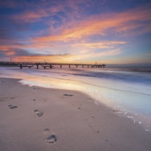 Pier on the fine sandy beach of the Baltic Sea at sunset, footprints in the sand, Baltic resort
