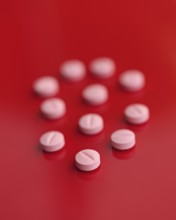 A striking image featuring several pink tablets casually dispersed on a saturated red backdrop,