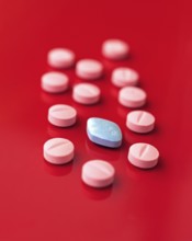 An image featuring a collection of pink tablets scattered on a striking red background, with a