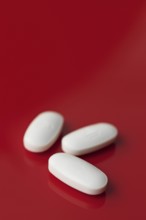 A minimalist image featuring three oblong white tablets, subtly embossed, isolated against a deep