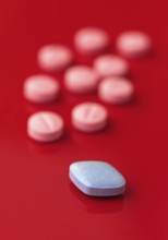 A vivid image showcasing a blue pill prominently in focus with several pink pills in the