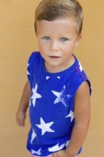 A young boy with blue eyes gazes upwards, wearing a blue shirt with white star patterns His