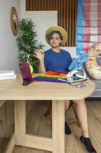 Transgender man hosting a virtual meeting from home, displayed on a smartphone. He is gesturing