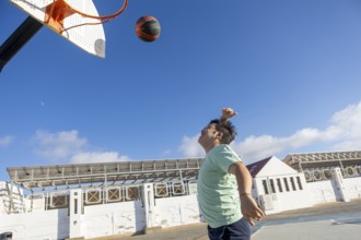 Teenager with Down syndrome playing basketball outdoors, emphasizing sports, captured in an open