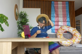 Transgender man hosting a virtual meeting from home, displayed on a smartphone. He is sitting at a