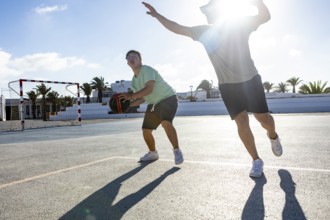 Down syndrome teenager joyfully plays basketball with his brother on an outdoor court The sun