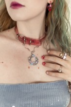 A stylish woman with a pink choker, rings, and earrings Her colorful hair complements the artistic