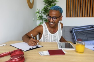 An LGBTQIA+ man enthusiastically prepares for holidays, jotting down plans at a table. Notebooks, a