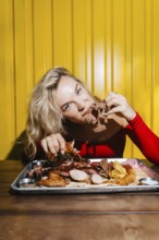 A woman savors a delicious barbecue platter filled with an assortment of meats against a bright