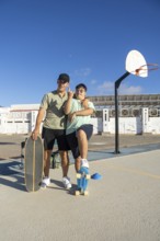 A teenager with Down Syndrome poses confidently with his brother and skateboards on an outdoor