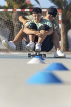 A teenager with Down syndrome enjoys a sporting activity with his brother, riding a skateboard