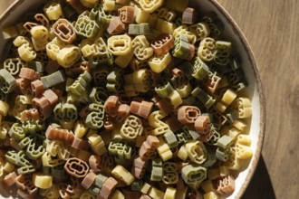 A bowl filled with multi-colored number shaped pasta featuring various digits. The numbers are not