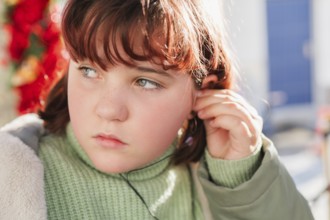 Close-up of a young girl adjusting her headphones, highlighting a thoughtful expression with a soft
