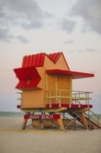 A colorful lifeguard stand at Miami Beach, featuring a bright red roof and yellow walls,