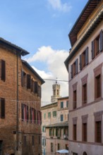 A picturesque street in Siena, Tuscany, framed by colorful traditional houses with wooden shutters.