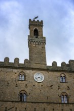 A close-up of the Priori Palace tower in Volterra, Tuscany, showcasing its medieval architecture
