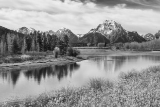 A serene black and white photograph, showcasing the majestic Tetons reflected in the still waters