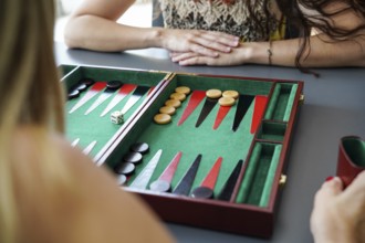 Close-up of a backgammon board with pieces and dice in play Mother and daughter are engaged in a