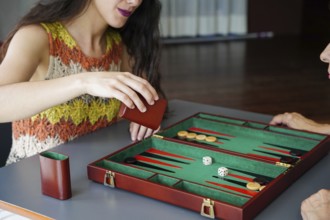 A woman engaging in a strategic game of backgammon, rolling the dice in anticipation A green and