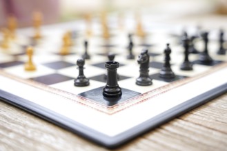 Close-up of a chessboard on a wooden table outdoors Black and white pieces arranged for a game in