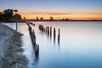 View at sunset over the Strelasund of the illuminated silhouette of the city of Stralsund with its