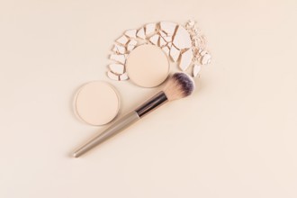 Top view of a styled makeup layout featuring compact powder in whole and broken forms, and loose