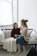 A heartwarming image of a woman and a young girl sitting on a sofa in a cozy living room, sharing a