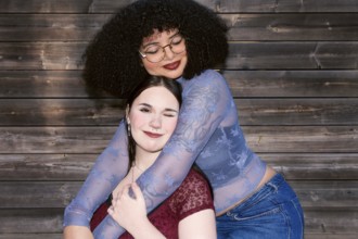 Two young Gen Z women, one Hispanic with curly hair, and the other of unspecified ethnicity, share