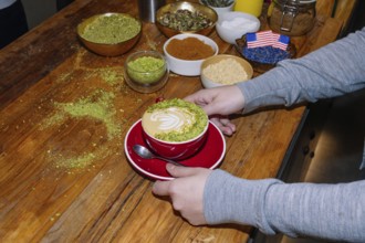 A delightful cup of specialty coffee crafted with intricate pistachio latte art on a wooden table.