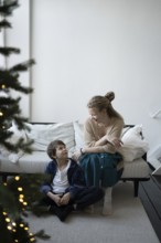A warm holiday moment, a mother and child share smiles in a cozy living room with festive decor A