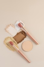Top view of compact and loose powders with makeup brushes on a neutral background. This shot