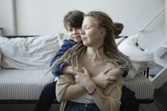 A tender moment between a mother and her son as they hug affectionately on a striped sofa The