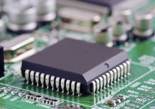 A detailed macro shot of a microchip securely mounted on a green printed circuit board,