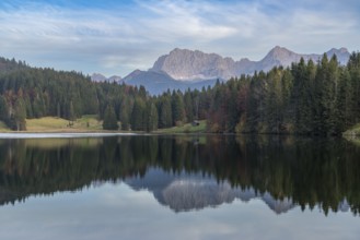 Tranquil Geroldsee with the stunning Bavarian Alps in the background Tall evergreens and rocky