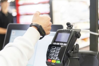 Cropped image of woman's hand making a payment using a smartwatch at a card terminal in a