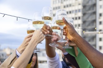 A vibrant group of friends raise their glasses in a rooftop toast, celebrating with joy and