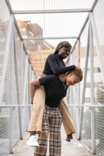 Two people share a joyful moment on a pedestrian bridge, with one playfully giving the other a